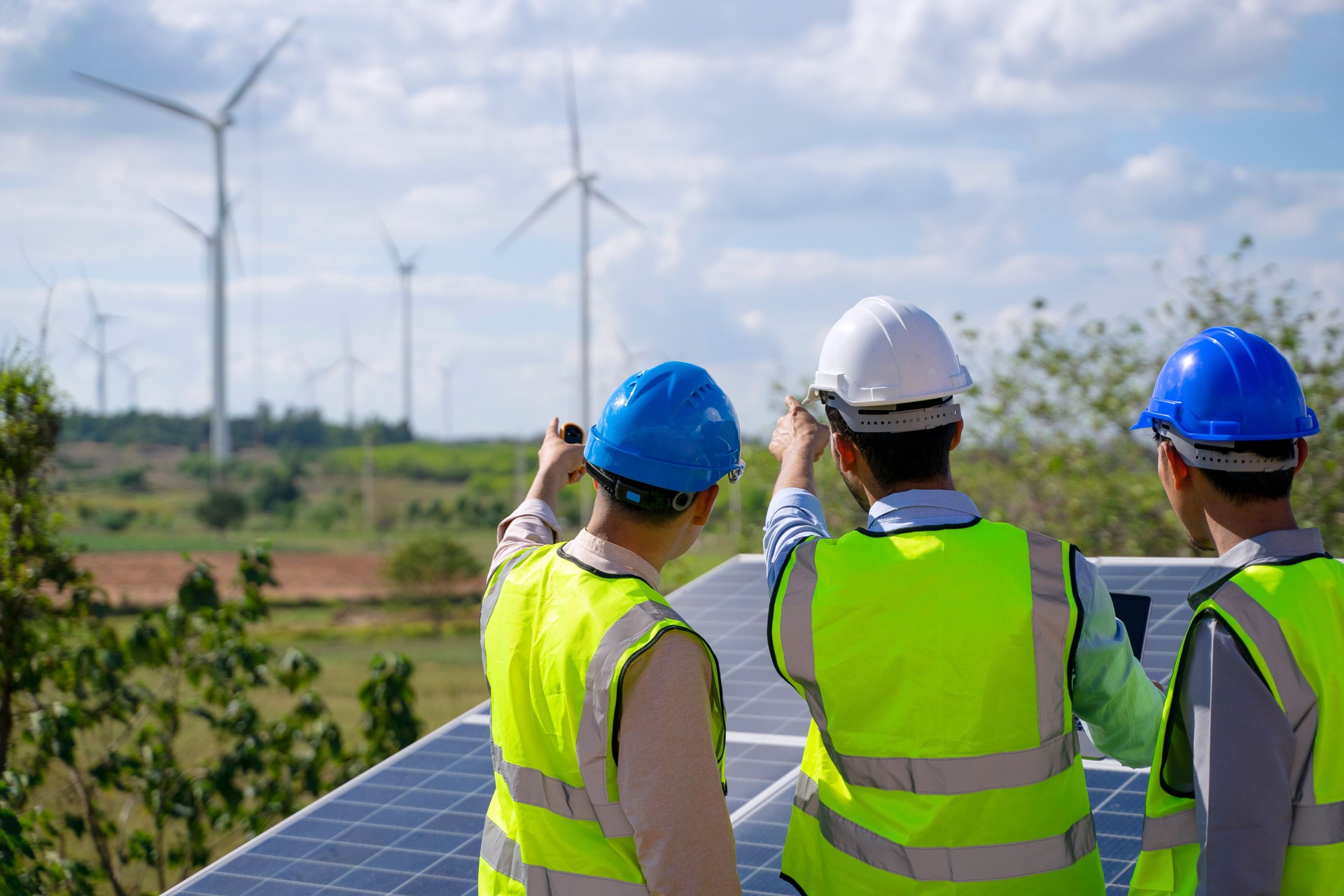 Blue collar workers at electricity site. Windmill field.